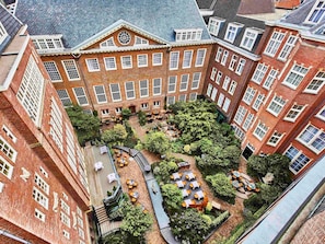 A courtyard with outdoor seating and a central garden area surrounded by brick buildings. - Sofitel Legend The Grand Amsterdam (Amsterdam)