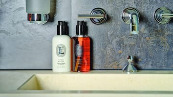 Une salle de bain avec un mur en marbre, un lavabo et deux flacons de lotion.