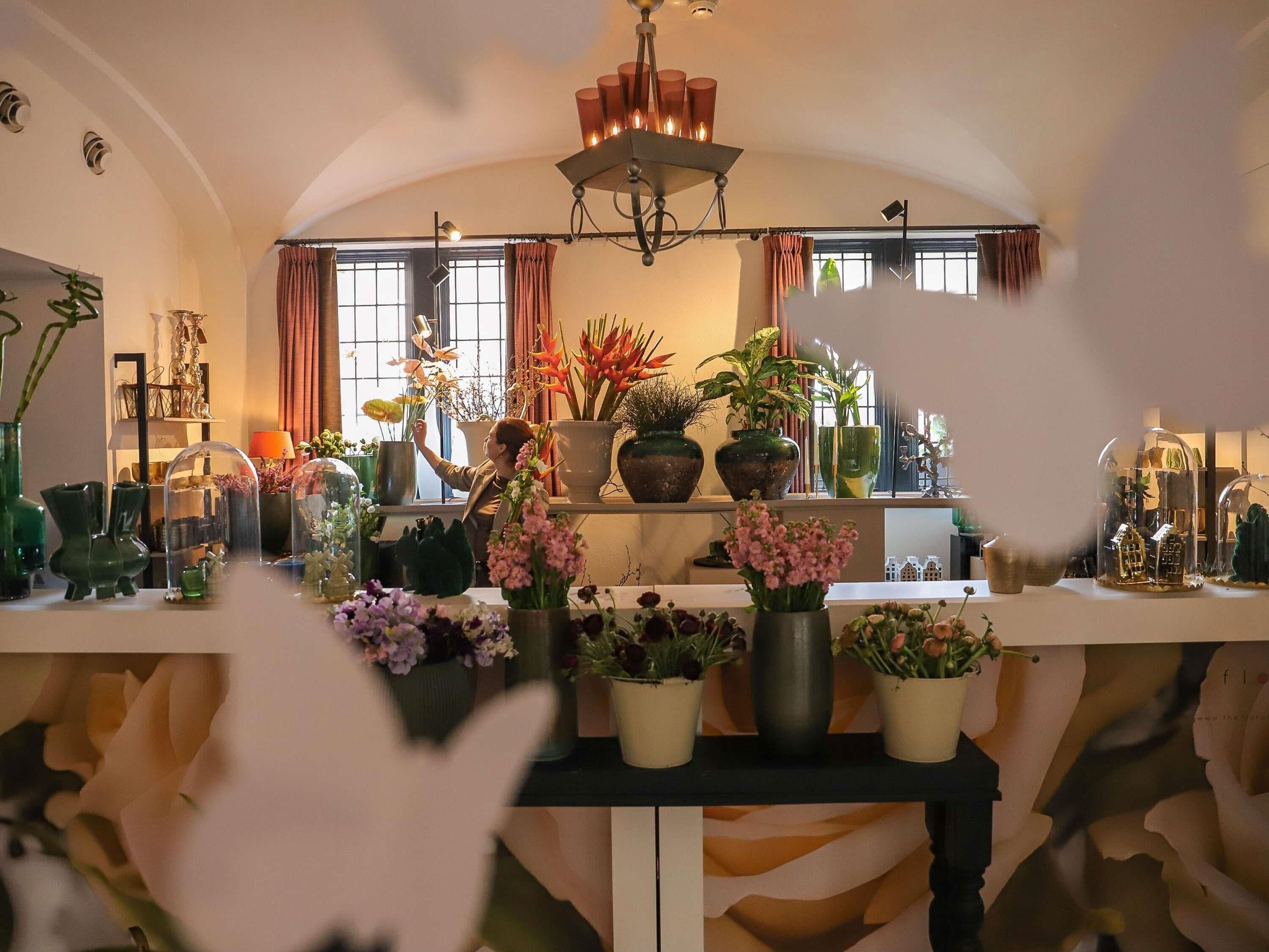 Um quarto com uma mesa comprida exibindo diversos vasos com plantas e flores.