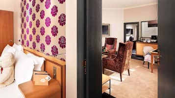 Habitación de hotel con cama, escritorio, silla y un papel tapiz con motivos florales.