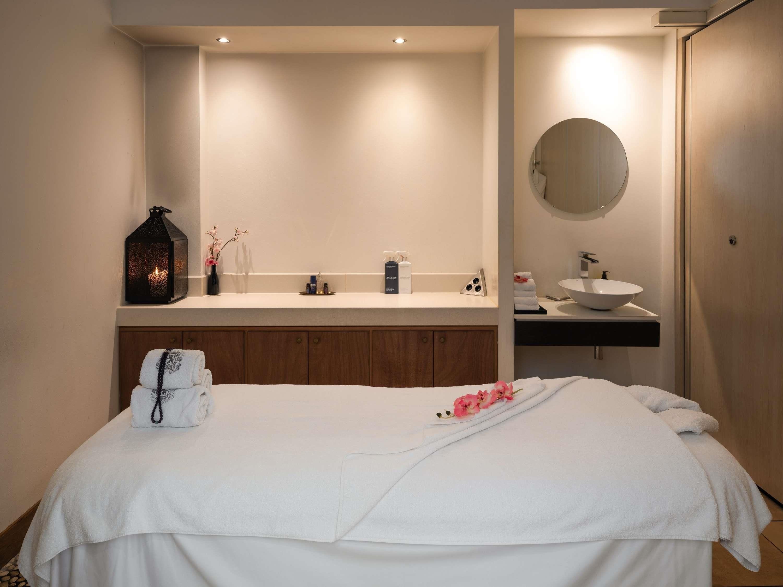 A modern bedroom with a bed, a vanity with a mirror, and a bedside table.
