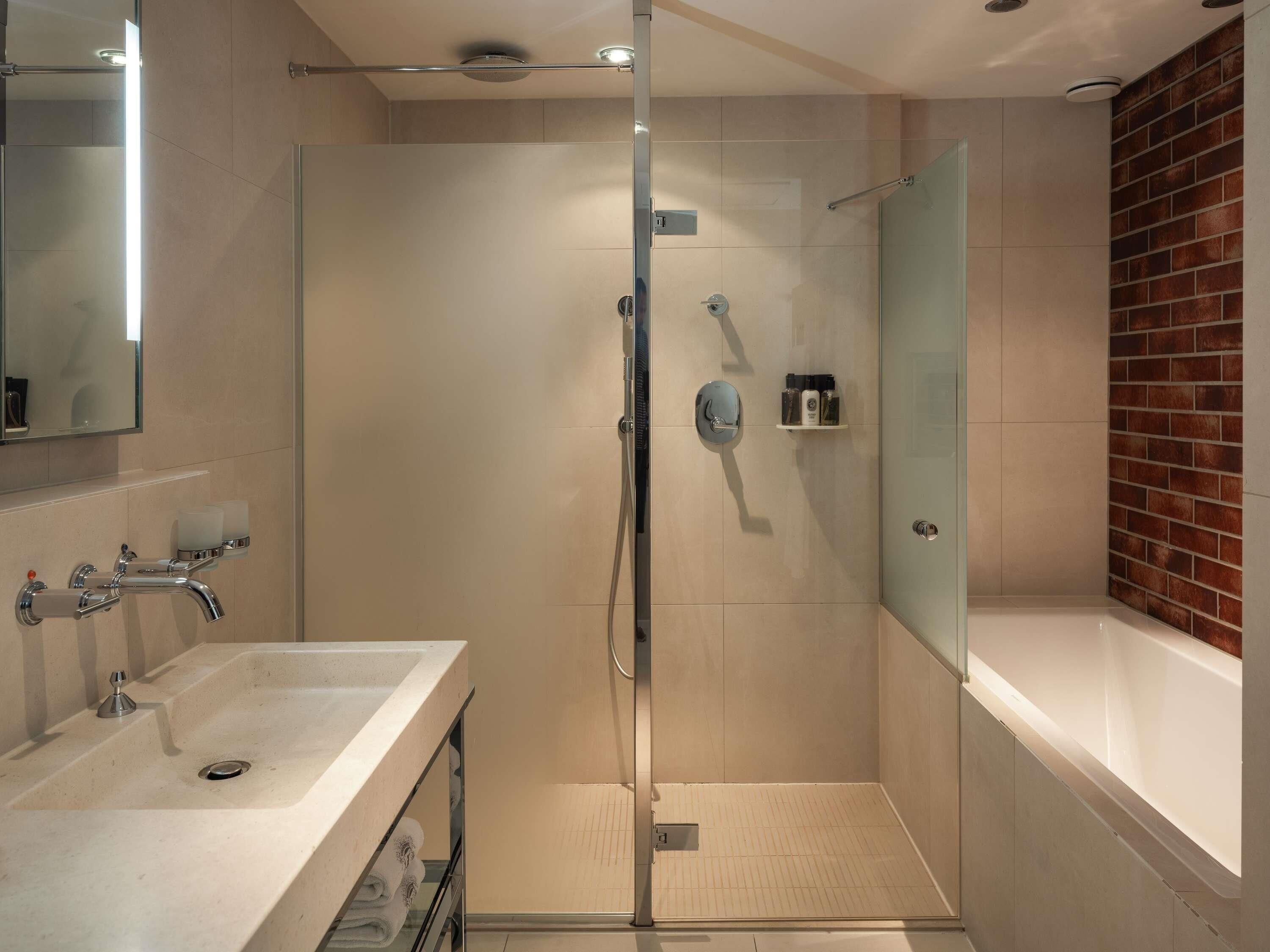 Un baño moderno con cabina de ducha de vidrio, bañera y tocador con lavabo.