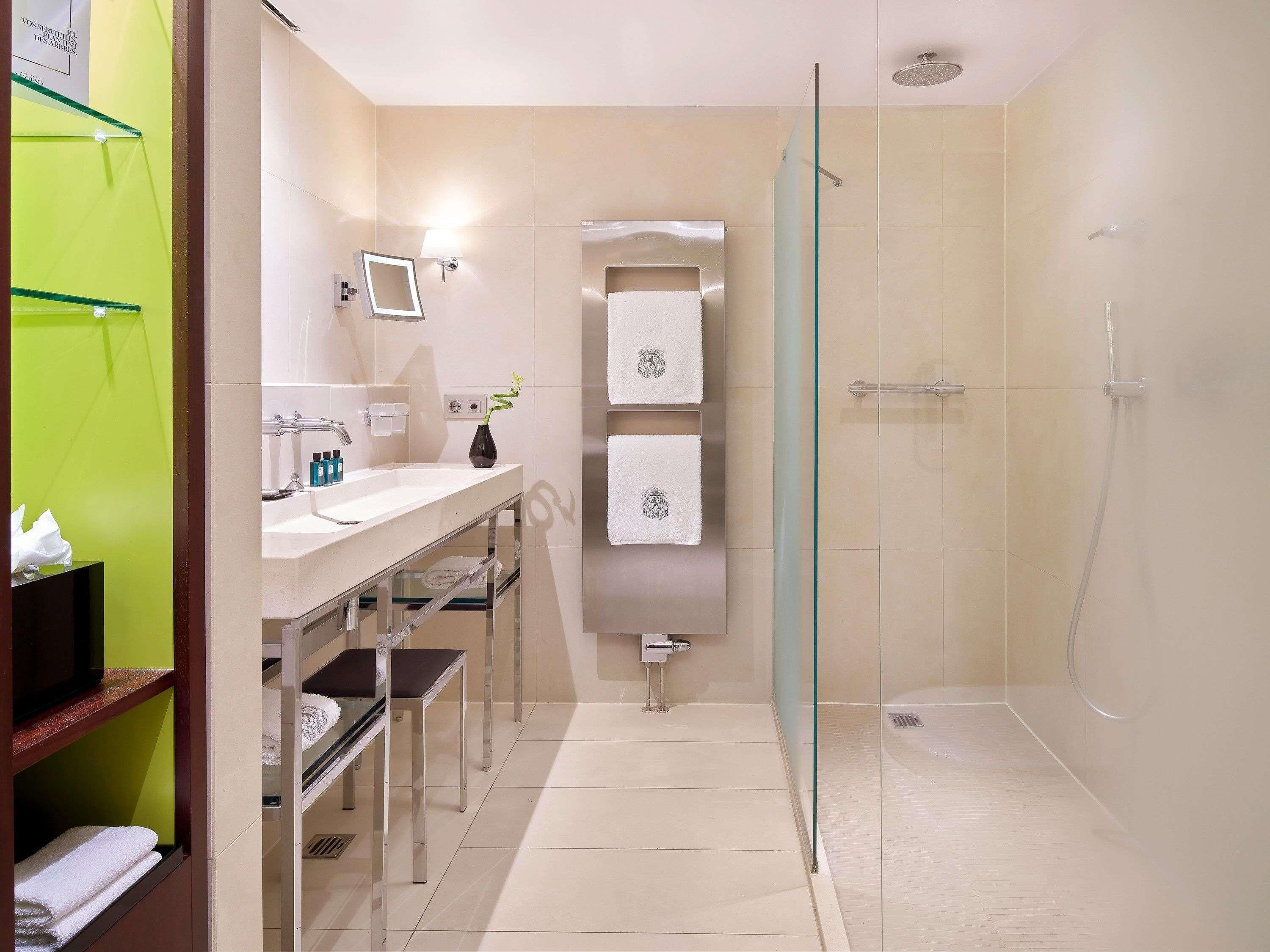A modern bathroom with a glass shower enclosure, a vanity with a mirror, and a shelf with towels.