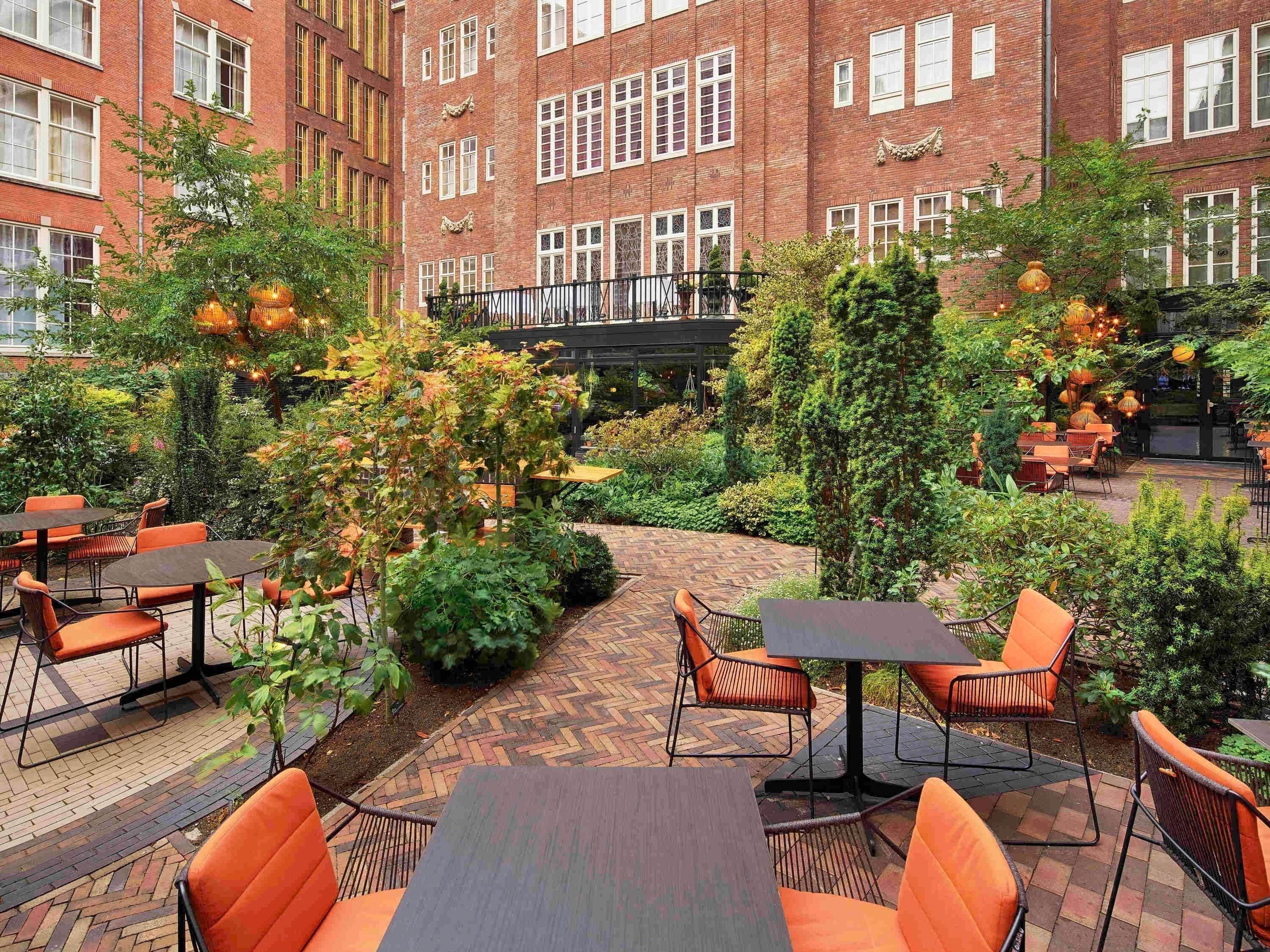 A courtyard with outdoor seating, brick buildings, and greenery.