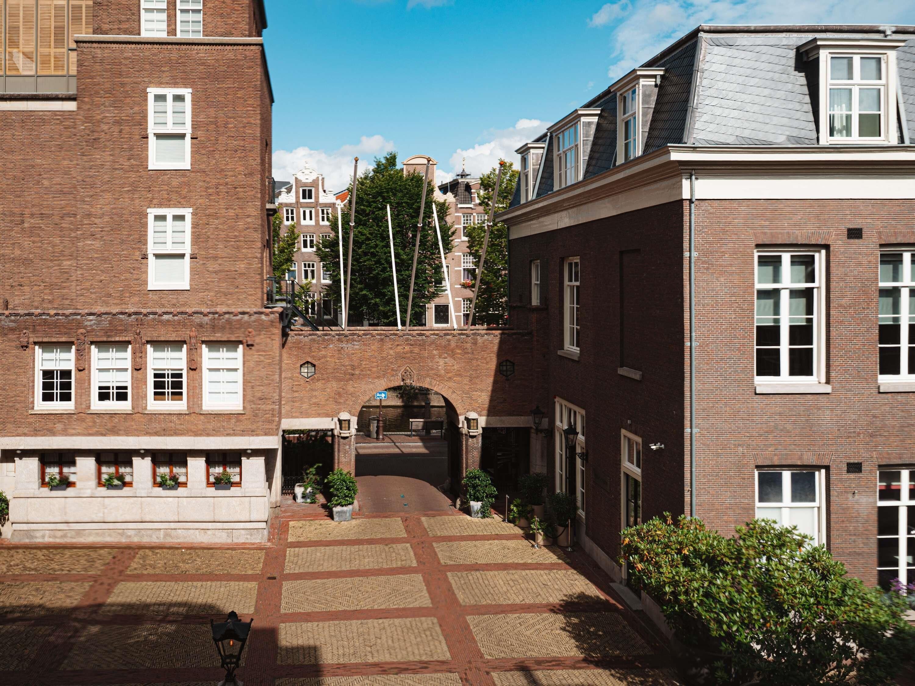 A courtyard with a brick building, a stone archway, and a bench.