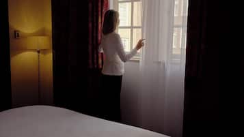 Una habitación de hotel con una cama, una lámpara y un ventanal con cortinas.