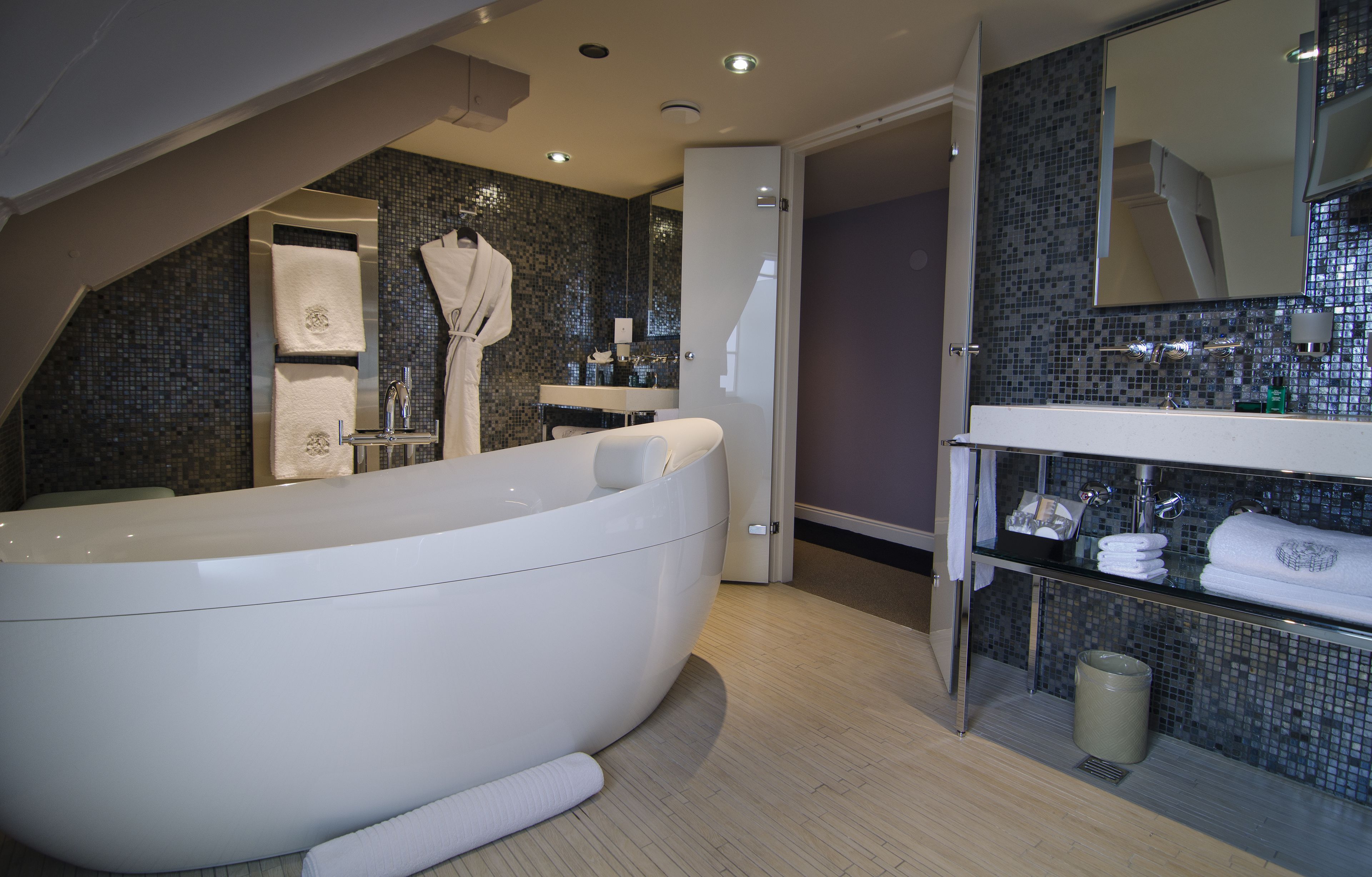 A modern bathroom with a freestanding bathtub, a glass-enclosed shower, and a vanity with a mirror.