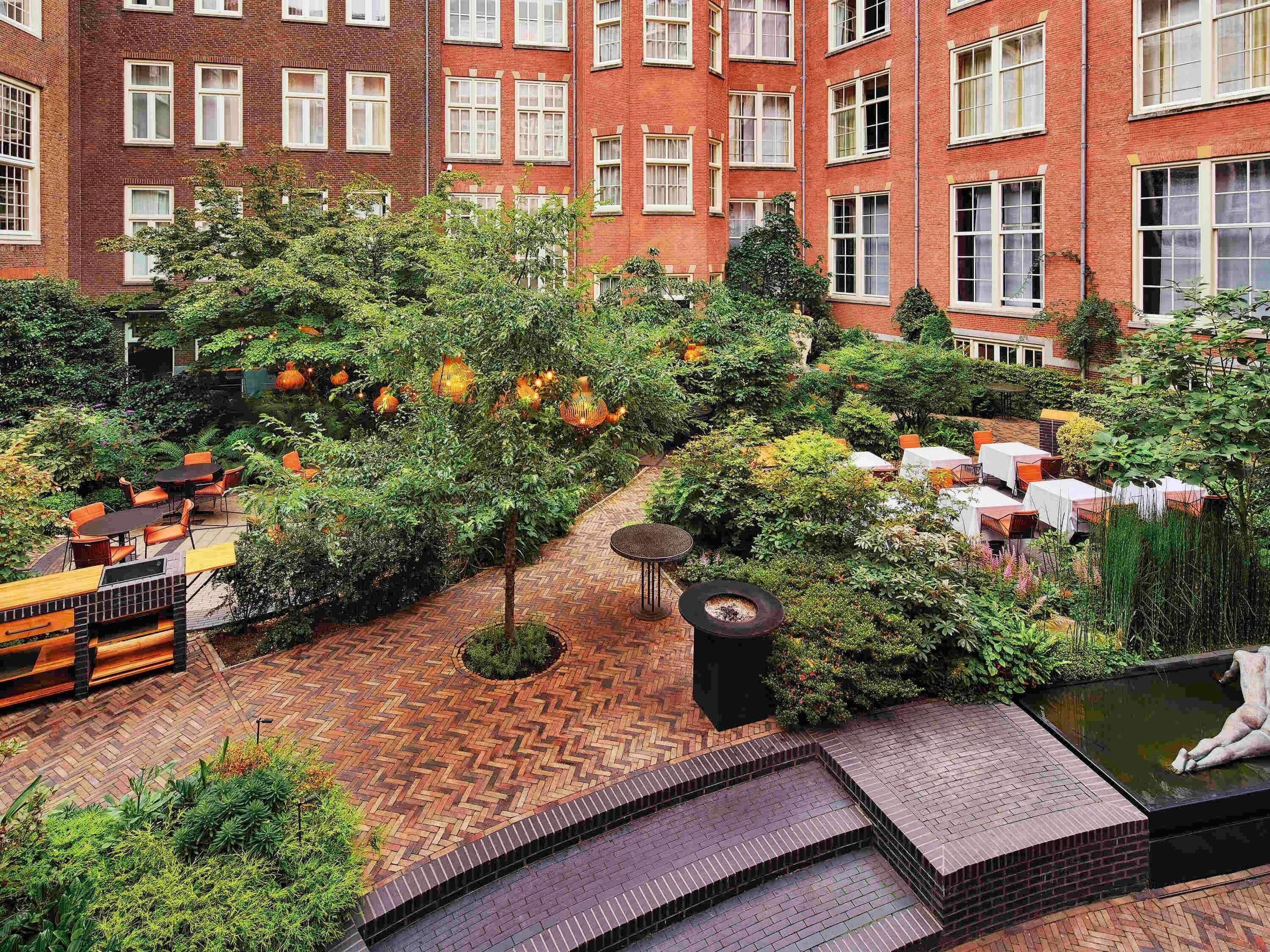 A courtyard with outdoor seating, a fire pit, and a pond with a statue.