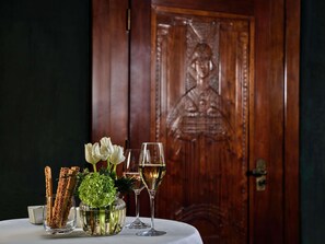 Una mesa con pasteles, un florero con flores y dos copas de vino blanco.