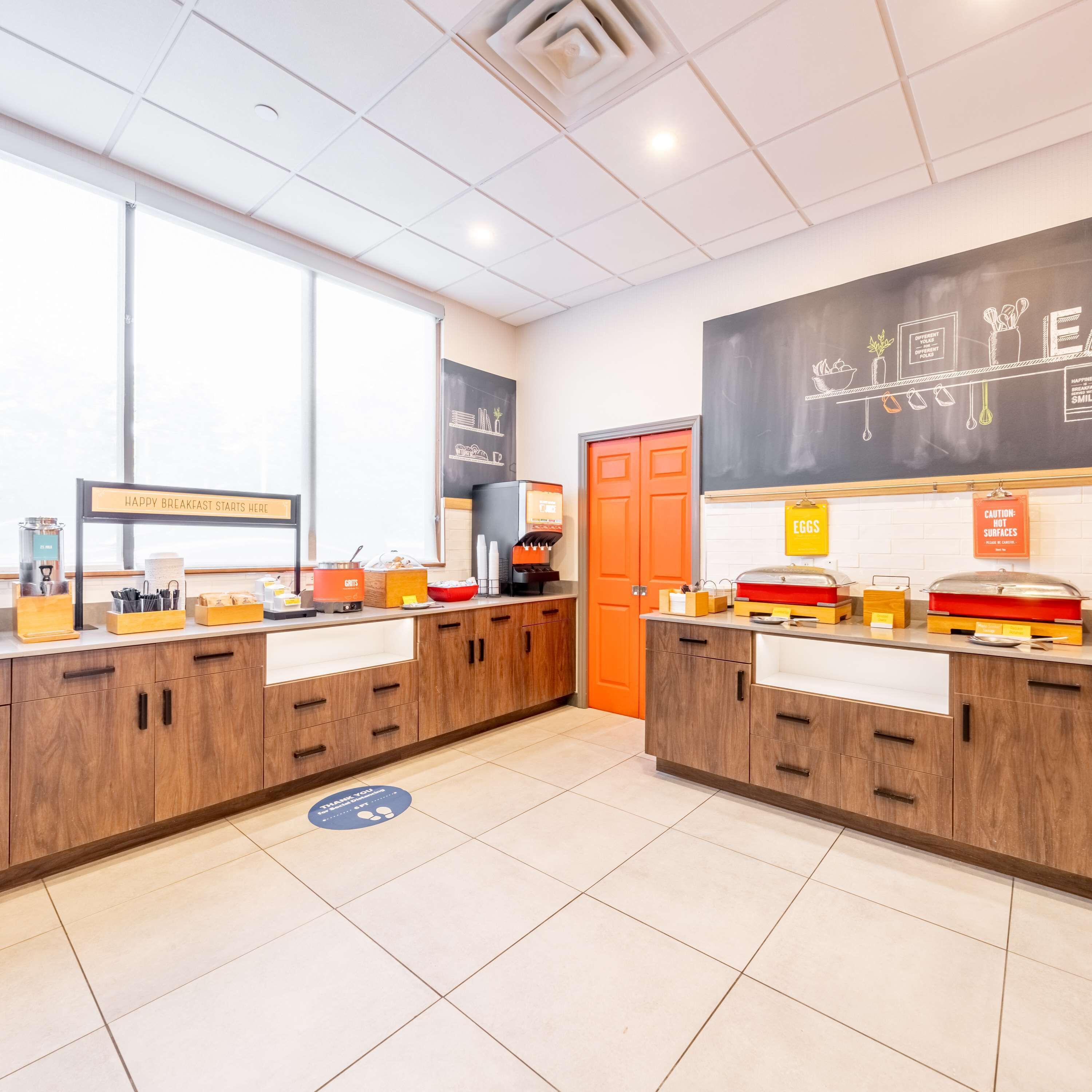 A breakfast area with two counters, a chalkboard menu, and a sign indicating hot surfaces.