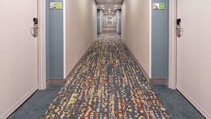 Un pasillo de hotel con pisos alfombrados, puertas a ambos lados e iluminación en el techo.