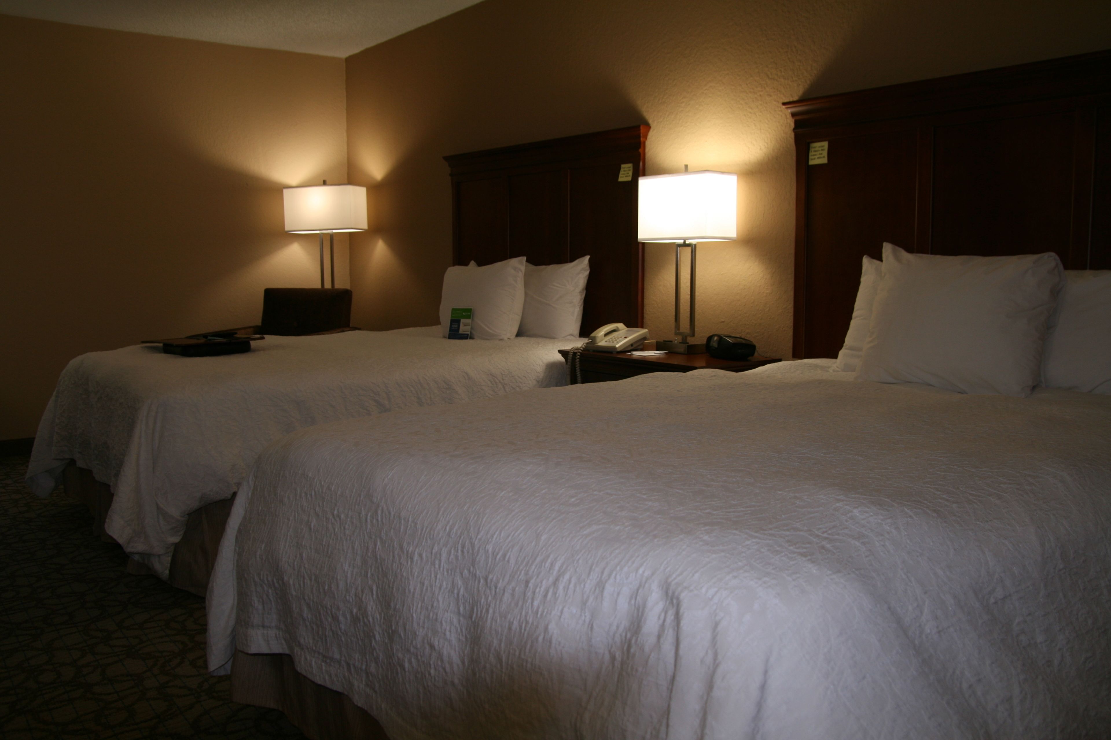 Une chambre d’hôtel avec deux lits, chacun étant équipé d’une table de chevet, d’une lampe et d’un téléphone.
