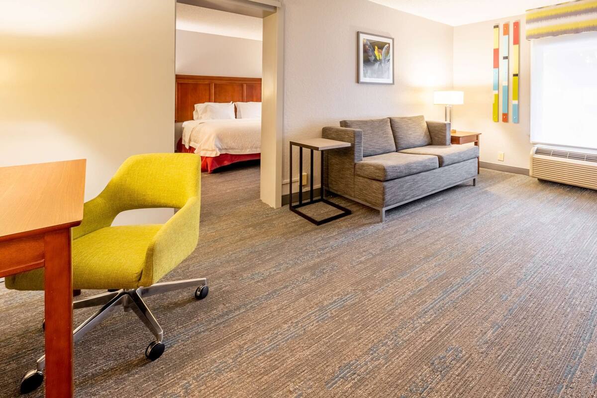 A hotel room with a bed, a sofa, a desk, and a chair.