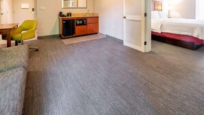 Habitación de hotel con kitchenette, cama, escritorio con silla y baño.