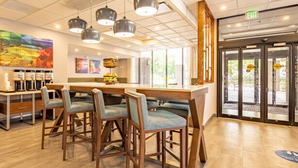 Un área de bar moderna con taburetes de madera, iluminación colgante y obras de arte en las paredes.