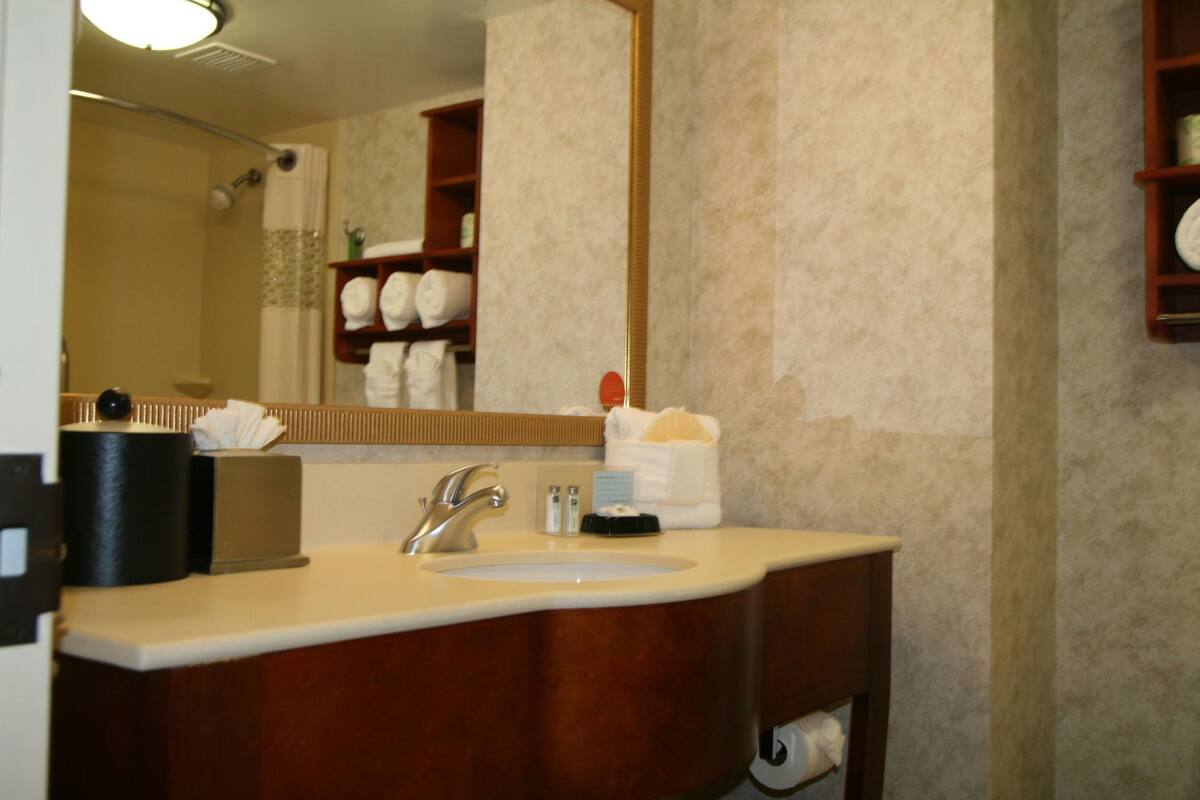 A bathroom with a sink, mirror, towel rack, and toiletries.