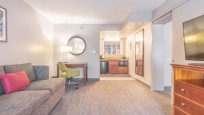 Habitación de hotel con sala de estar, kitchenette y un espejo grande.