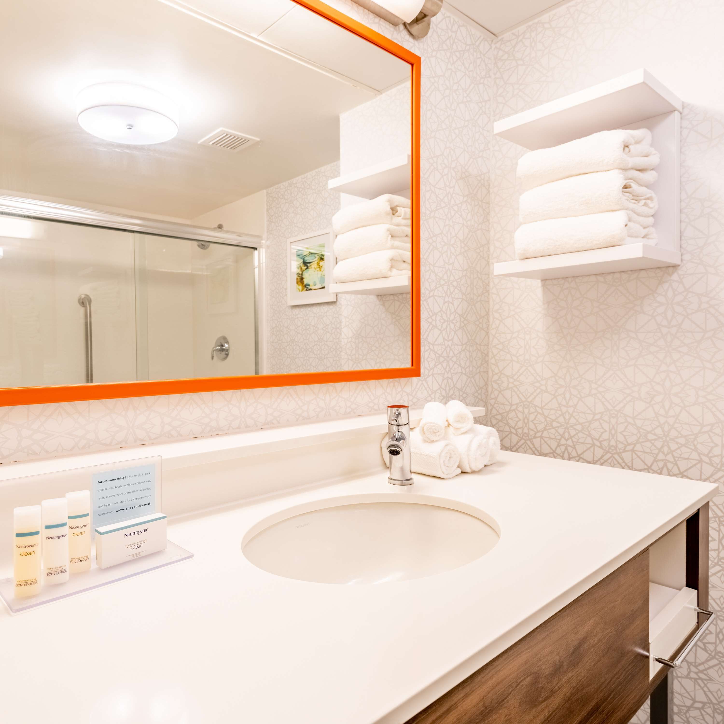 Un bany modern amb un mirall gran, un lavabo i tovalloles ordenades sobre prestatgeries.