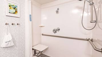 A modern bathroom with a shower, grab bars, a small toilet, and a towel rack.