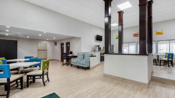 A spacious dining area with multiple tables and chairs, a reception desk, and a large mirror on the wall. - Quality Inn Coraopolis - Pittsburgh Airport (Coraopolis)