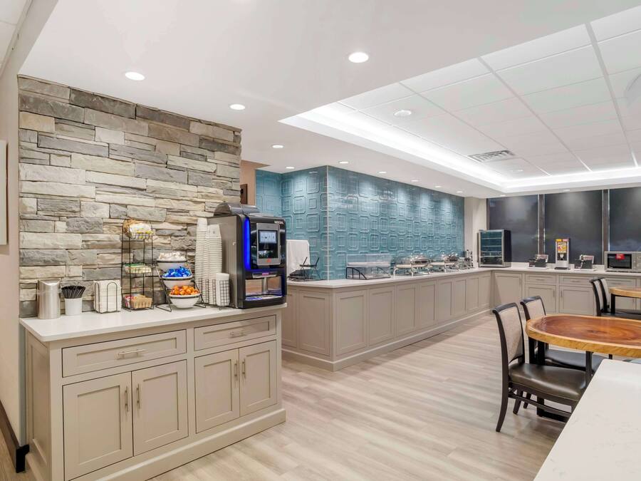 A modern kitchen with a stone backsplash, a built-in coffee station, and a dining area with a round wooden table and chairs.