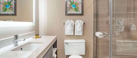 Een moderne badkamer met een douchecabine van glas, een wit toilet en twee ingelijste bloemwerk afbeeldingen aan de wand.