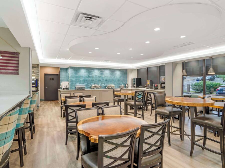 A modern restaurant with a bar area, wooden tables, and chairs.