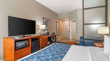 A hotel room with a bed, a desk with a TV, a microwave, and a coffee maker.