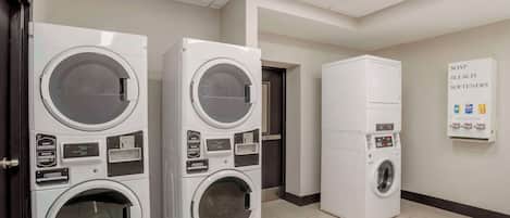 A laundry facility with multiple stacked washing machines and a sign indicating the availability of soap, bleach, and softeners.