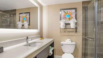Un baño moderno con un espejo grande, un lavabo, un inodoro y una zona de ducha.