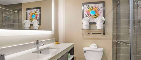 A modern bathroom with a large mirror, a sink, a toilet, and a shower area.