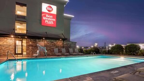 Zona de piscina con sillas de descanso y un cartel de Best Western Plus.