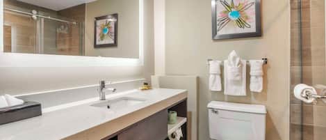 A modern bathroom with a large mirror, a dual sink vanity, a toilet, and a shower area.