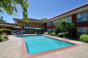Relax by the rectangular pool surrounded by lounge chairs and umbrellas.