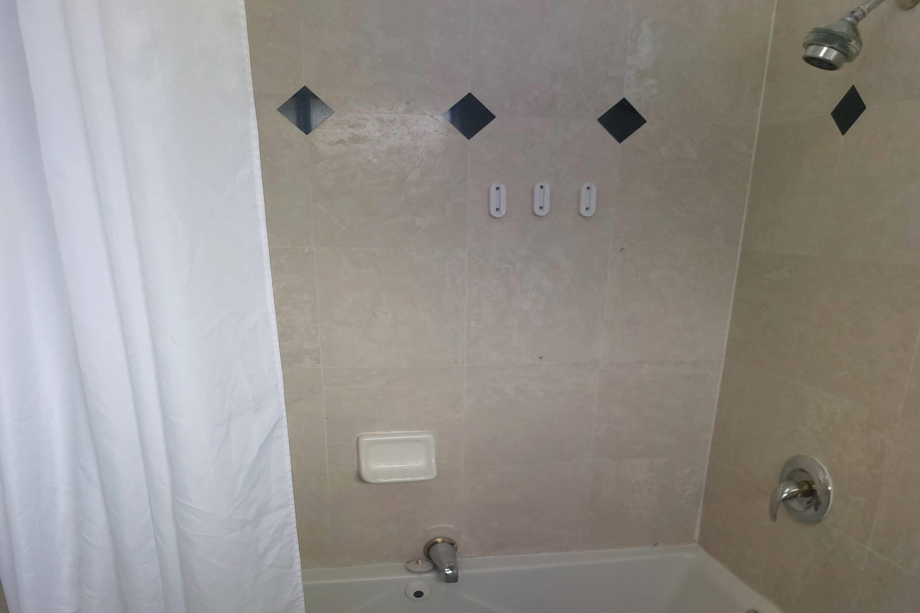 A bathroom with a bathtub, a showerhead, and a toilet.
