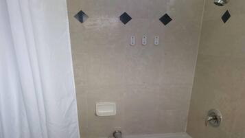 A bathroom with a bathtub, a showerhead, and a toilet.