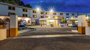 A hotel with multiple floors, a parking area, and a well-lit entrance. - ibis Evora Hotel (Évora)