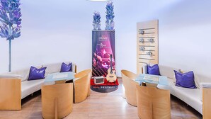 A modern lounge area with a central promotional stand, wooden furniture, and a decorative plant. - ibis Evora Hotel (Évora)