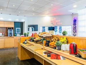 Una barra de desayuno con diferentes opciones de comida, una máquina de café y un letrero que dice "START ME UP".