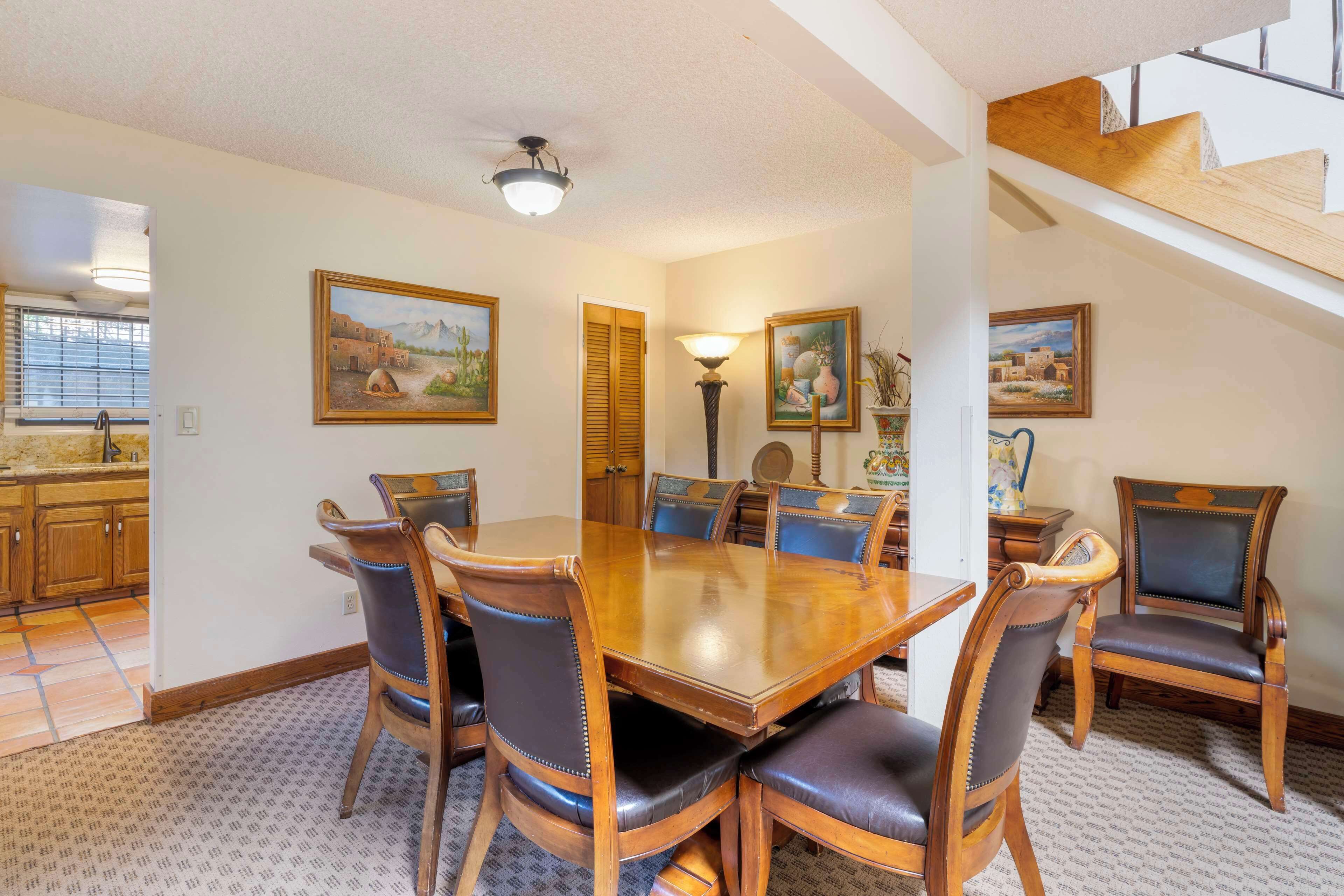 A dining area with a wooden table and chairs, surrounded by walls with framed artwork.