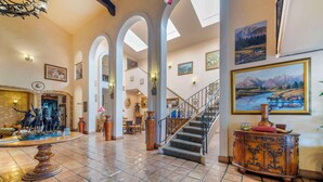 A spacious lobby with a tiled floor, a staircase, and a fireplace with a statue. - Best Western Casa Grande Inn (Pismo Beach)