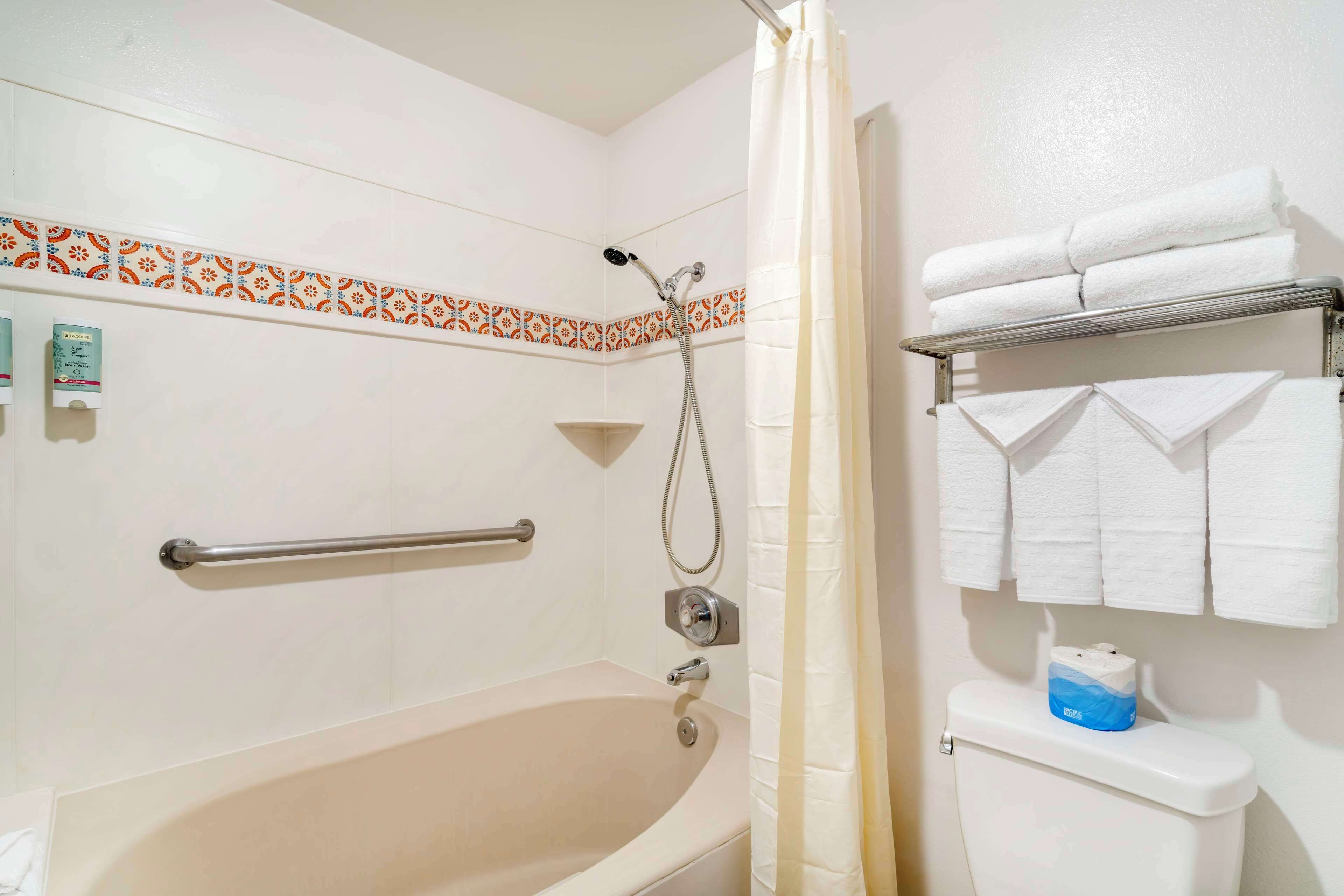 A bathroom with a bathtub, a shower, a toilet, and a towel rack with towels.