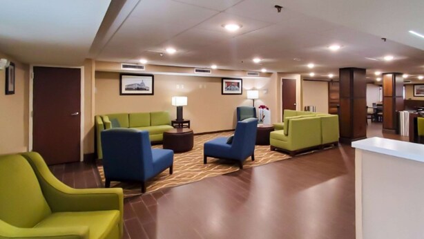 A hotel lobby with green and blue seating, a reception desk, and framed pictures on the walls.