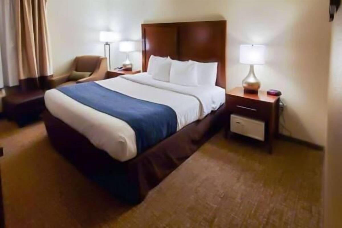 Ein Hotelzimmer mit einem großen Bett, einem Sessel, einem Nachttisch mit Lampe und einer Kommode.