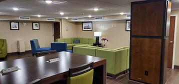 A conference room with a wooden table, blue and green chairs, and a green sofa.