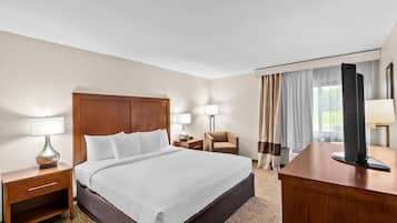 Habitación de hotel con una cama grande, lámparas de noche, un escritorio, una silla y un televisor.