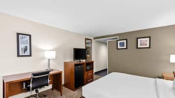 A hotel room with a bed, desk, chair, television, and a microwave.