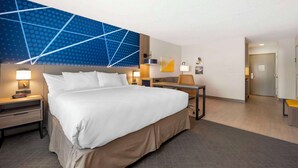 A hotel room with a large bed, bedside tables with lamps, a desk, and a modern blue wall design. - Comfort Inn Edinburgh - Columbus (Edinburgh)