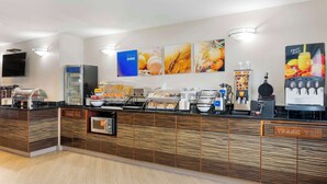 A breakfast bar with a variety of food options, a coffee machine, and a fruit juice dispenser. - Comfort Inn Edinburgh - Columbus (Edinburgh)