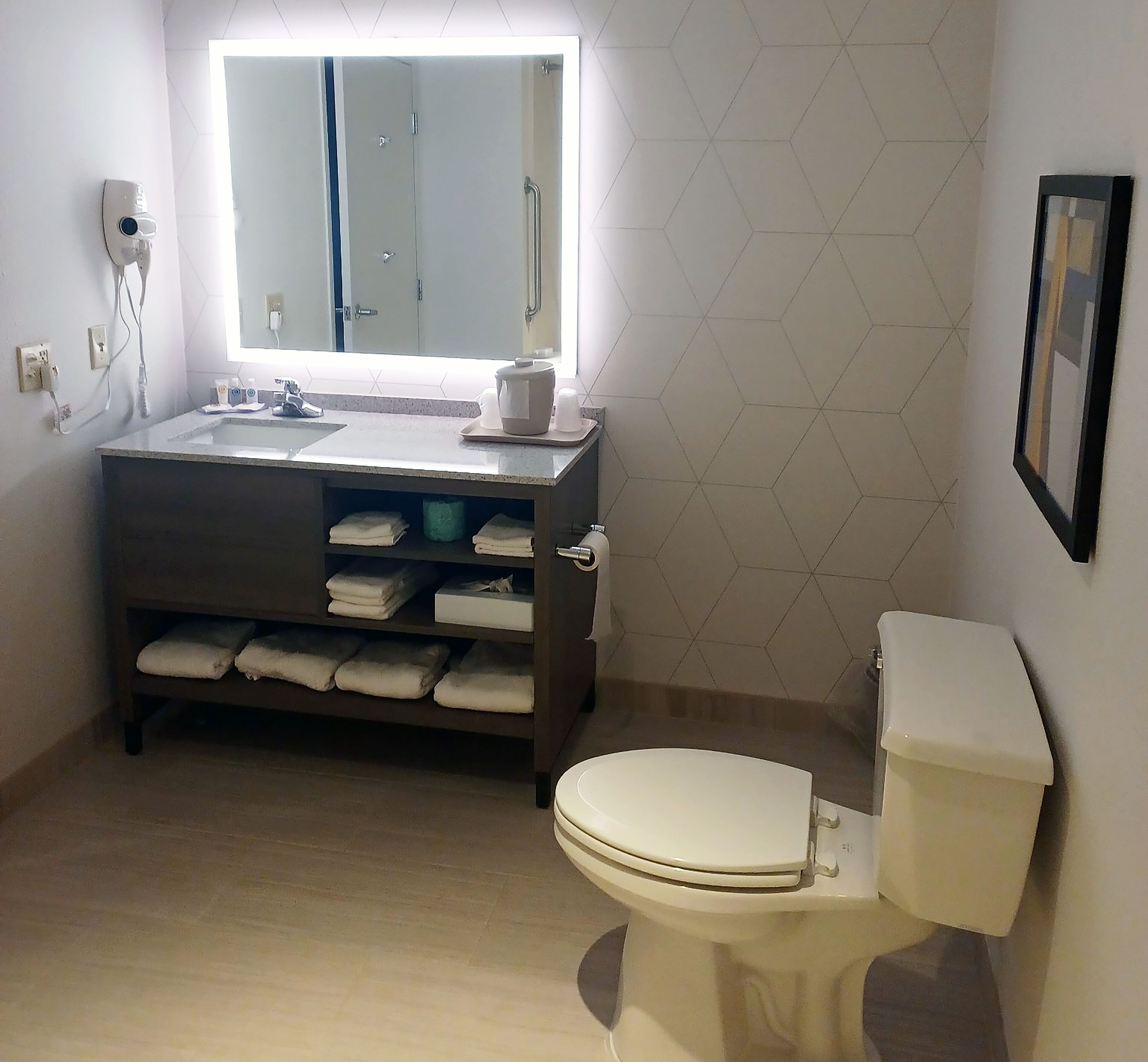 A bathroom with a toilet, sink, and mirror.